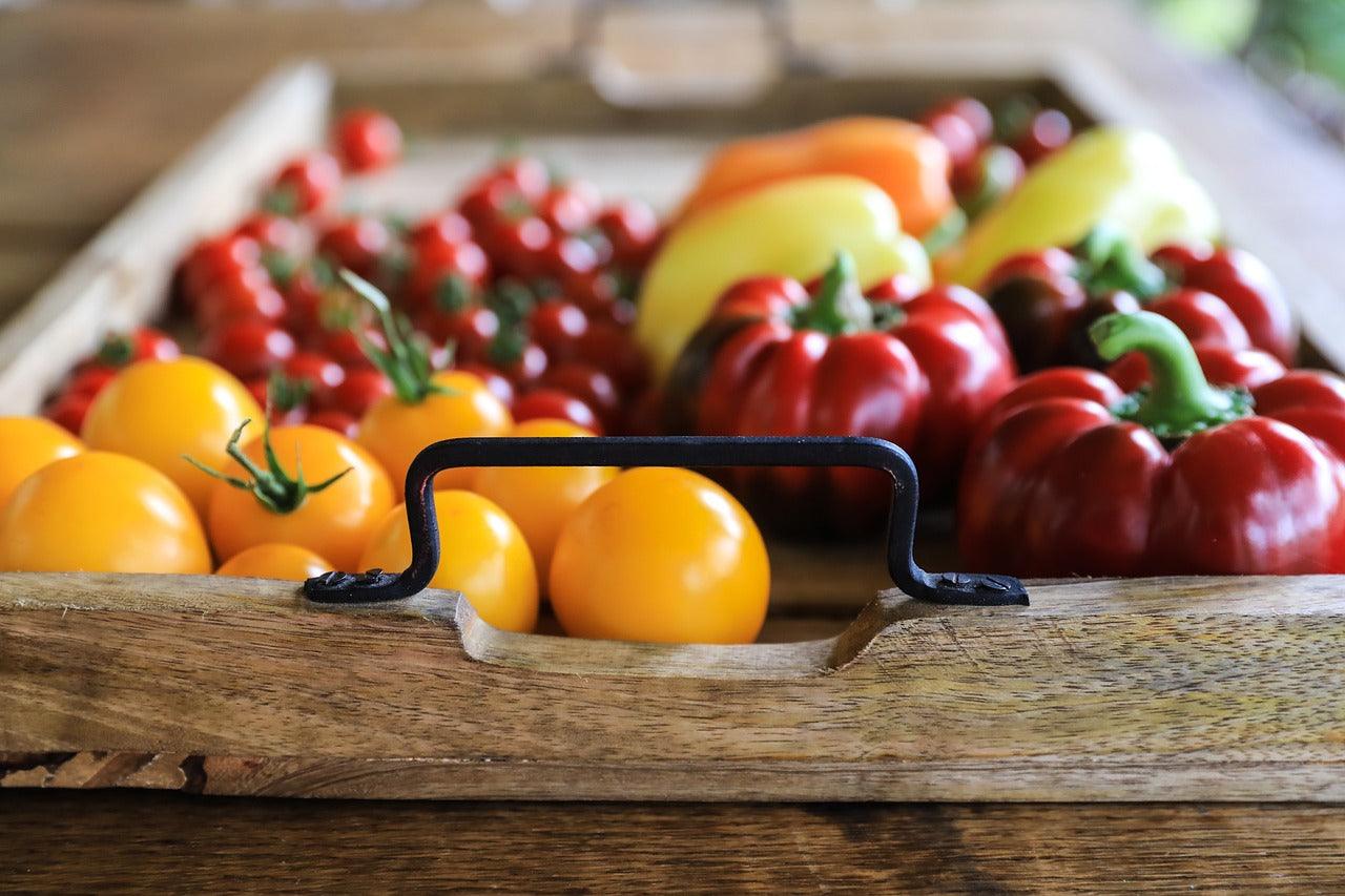 Fresh garden tomatoes and peppers in rustic wooden tray with metal handles