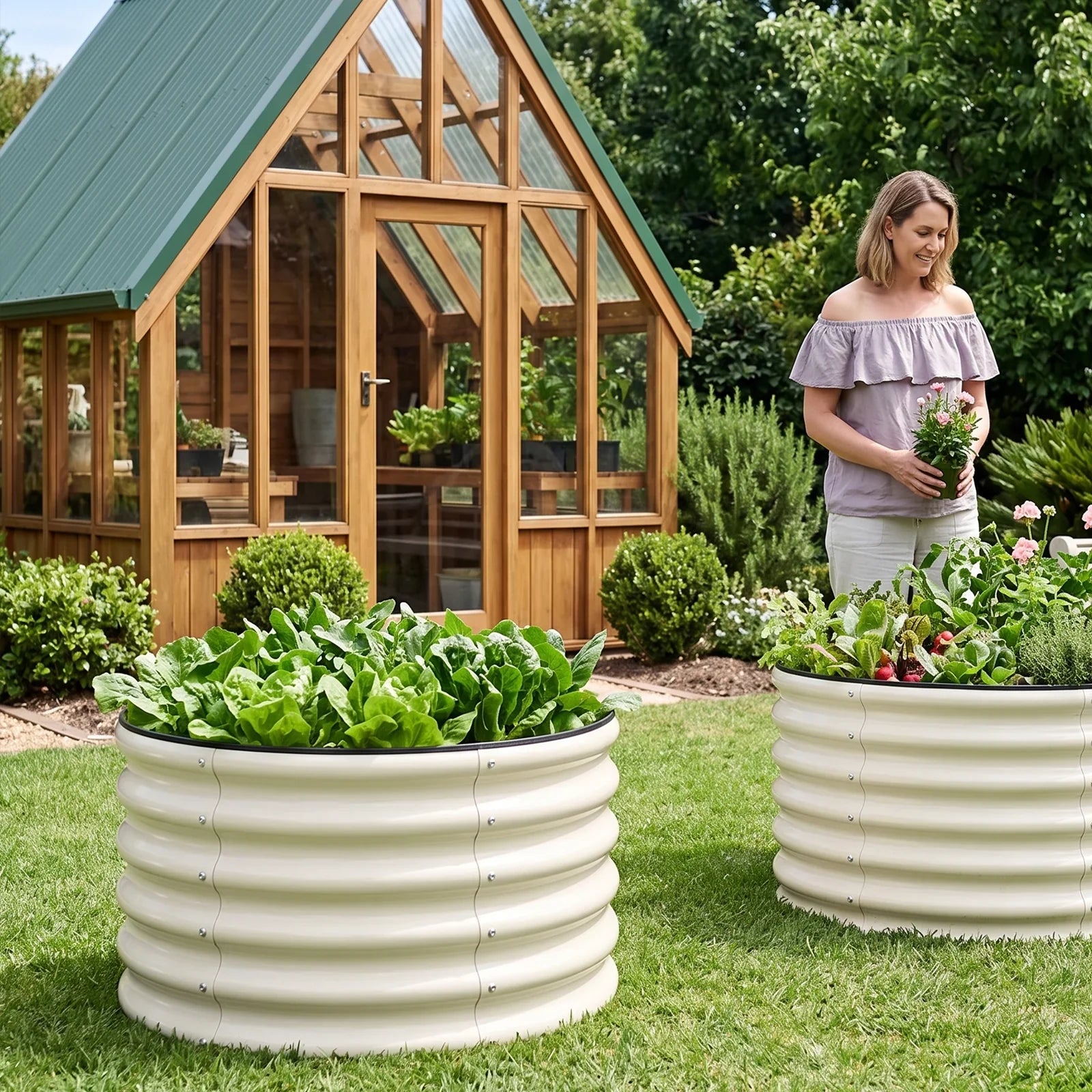 Metal raised garden beds with lush greens and flowers, perfect for backyard gardening near a greenhouse.