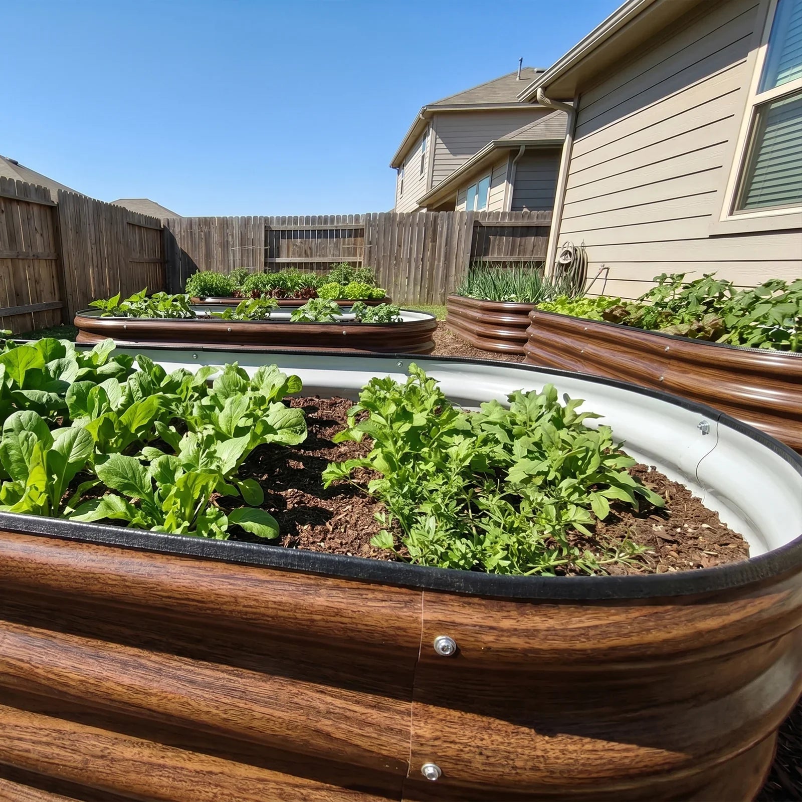 Metal raised garden beds with wood grain finish, filled with thriving green plants in a sunny backyard.