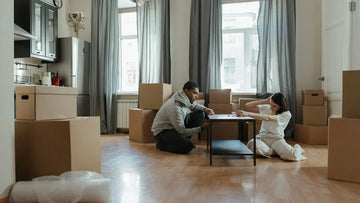 Couple assembling modern black side table surrounded by moving boxes in bright apartment