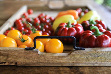 Fresh garden tomatoes and peppers in rustic wooden tray with metal handles