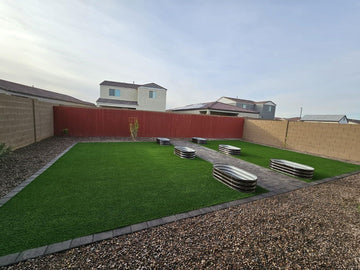 Metal raised garden beds on artificial turf in a backyard with gravel and pavers